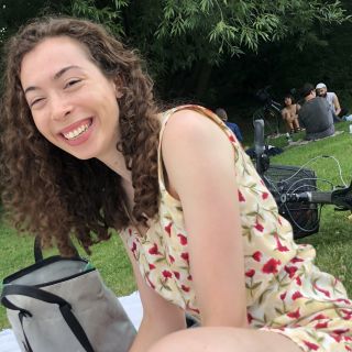 Person with long curly hair wearing a sundress at a park