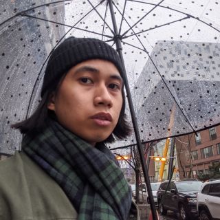 person looking at camera while holding an umbrella on a rainy, cloudy day