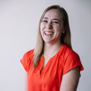 person wearing a bright orange shirt with long blonde hair laughing