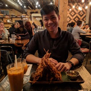 person sitting in a restaurant with a plate of food in front of them smiling