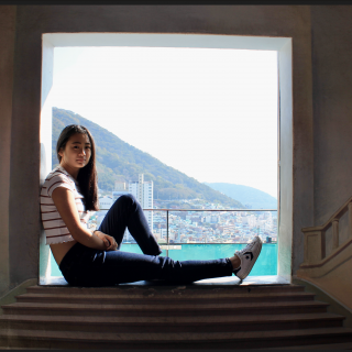 person sitting in a window frame with an ocean behind them