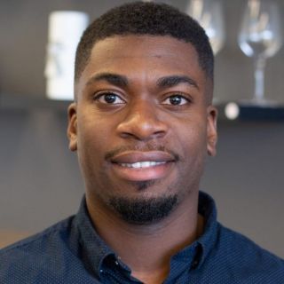 person wearing a blue collared shirt smiling at camera