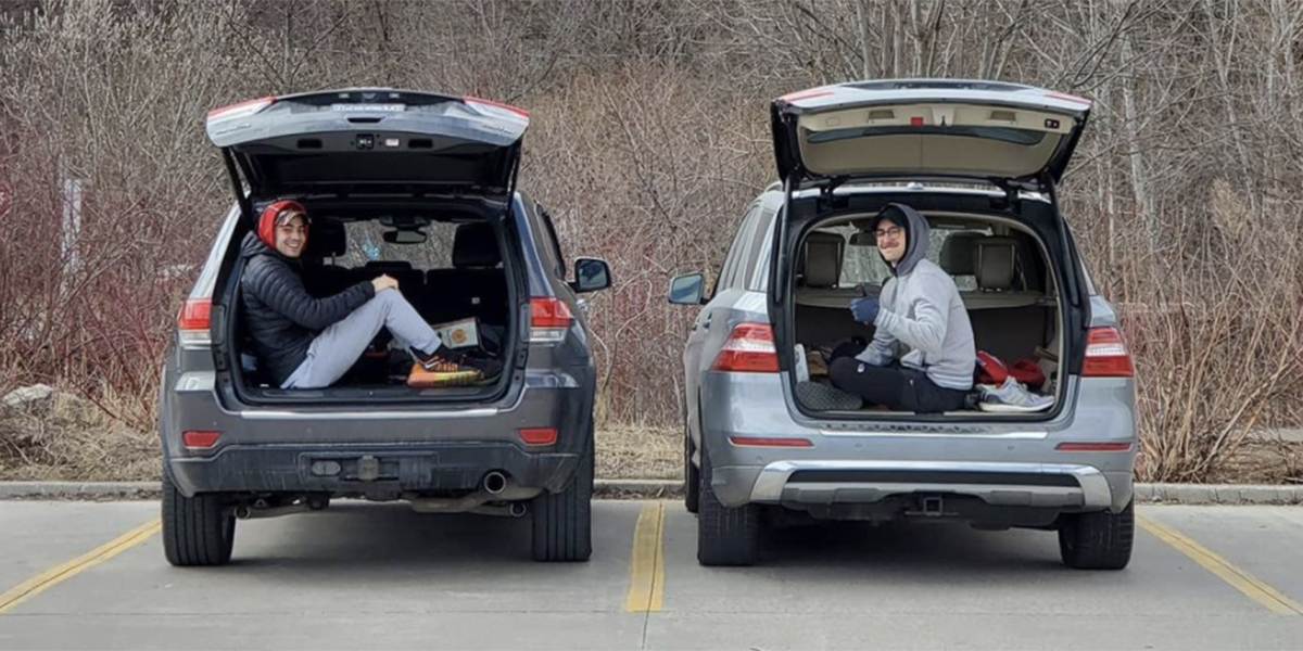 Two people at Evergreen Brick Works sitting in the truck of their individual cars with cups of coffee Image: @erinleethompson25 via Instagram